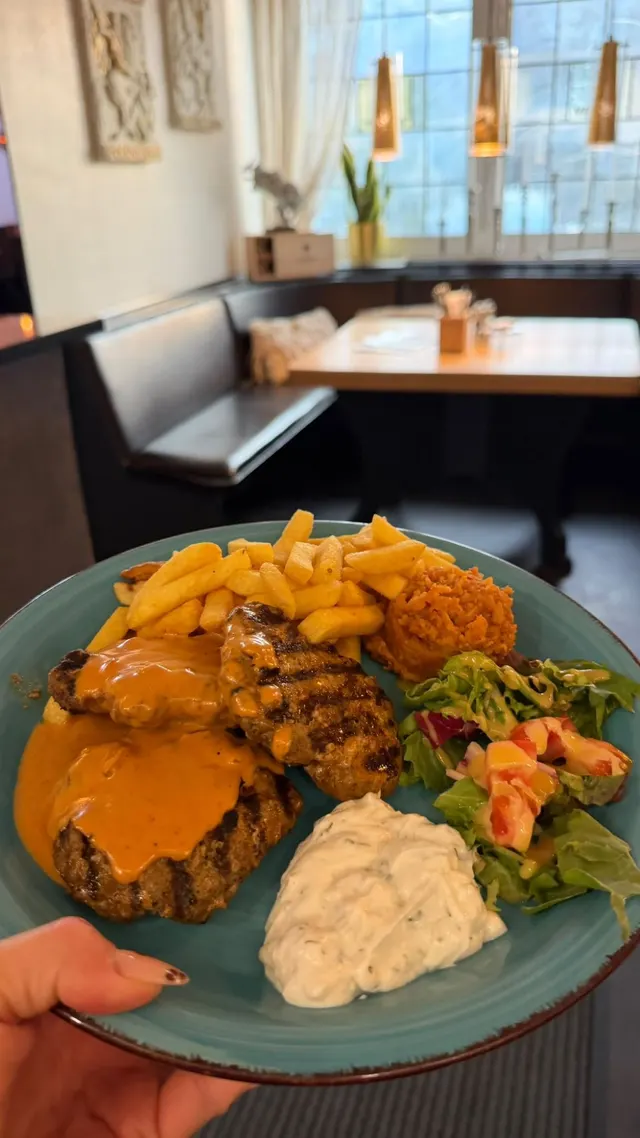 Gegrillte Bifteki mit Metaxasauce, Pommes, Tomatenreis, Zaziki und Salat