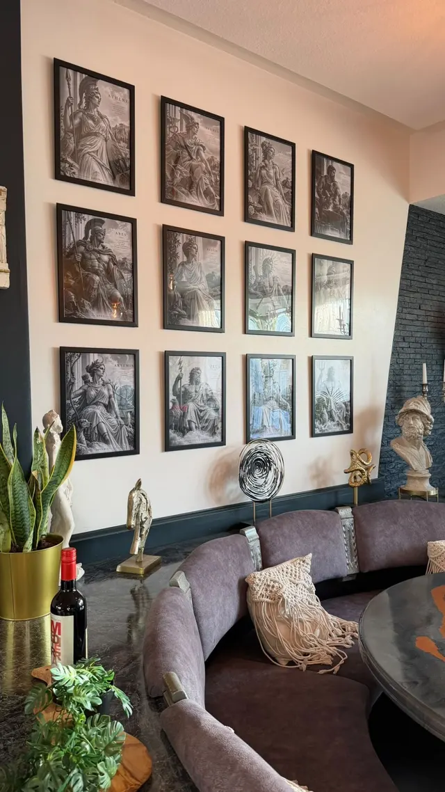 Gastraum mit einer Wand aus Bildern griechischer Götter, Büste und runder Sitzecke