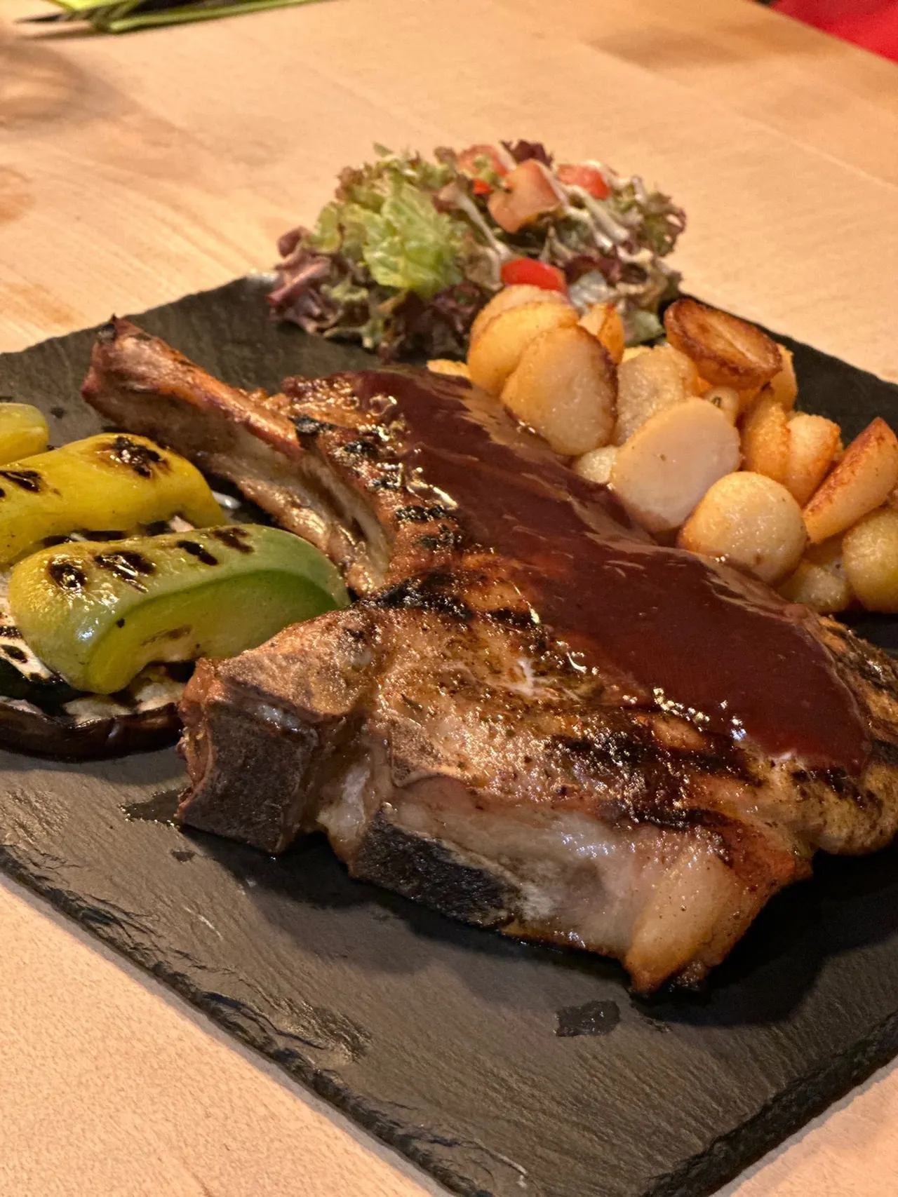 Gegrilltes Kotelett mit dunkler Sauce, Röstkartoffeln und Beilagensalat