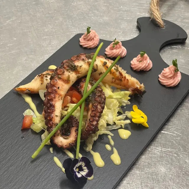 Gegrillter Oktopus auf Salatbett mit essbaren Blüten
