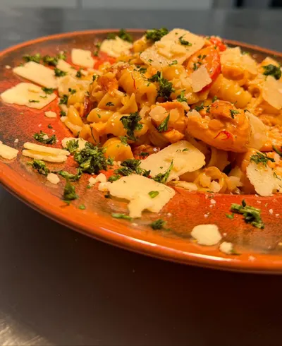 Pasta mit Parmesan und frischen Kräutern auf einem orangefarbenen Teller