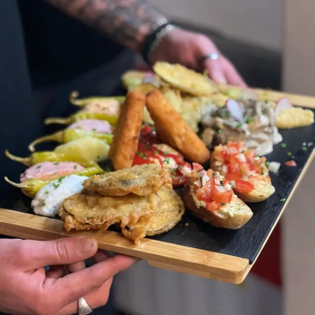 Holzbrett mit verschiedenen Tapas, Bruschetta, Dips und frittiertem Gemüse